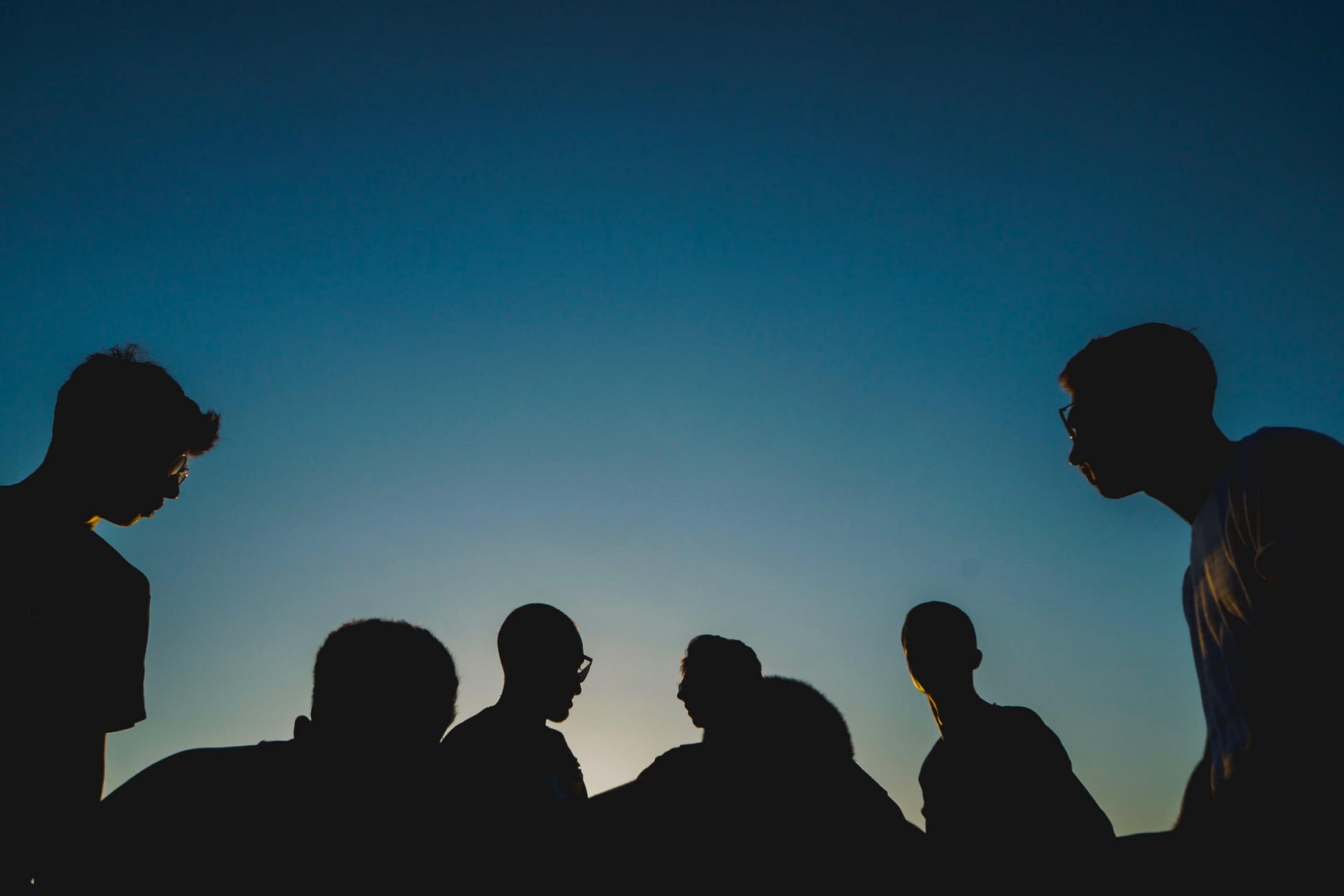 silhouette of people's head under the dark blue sky